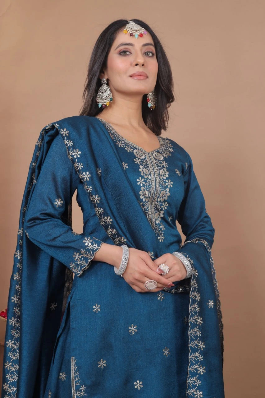 Woman wearing a blue embroidered traditional outfit against a brown background