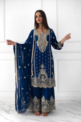Woman wearing a blue embroidered traditional outfit with a white background