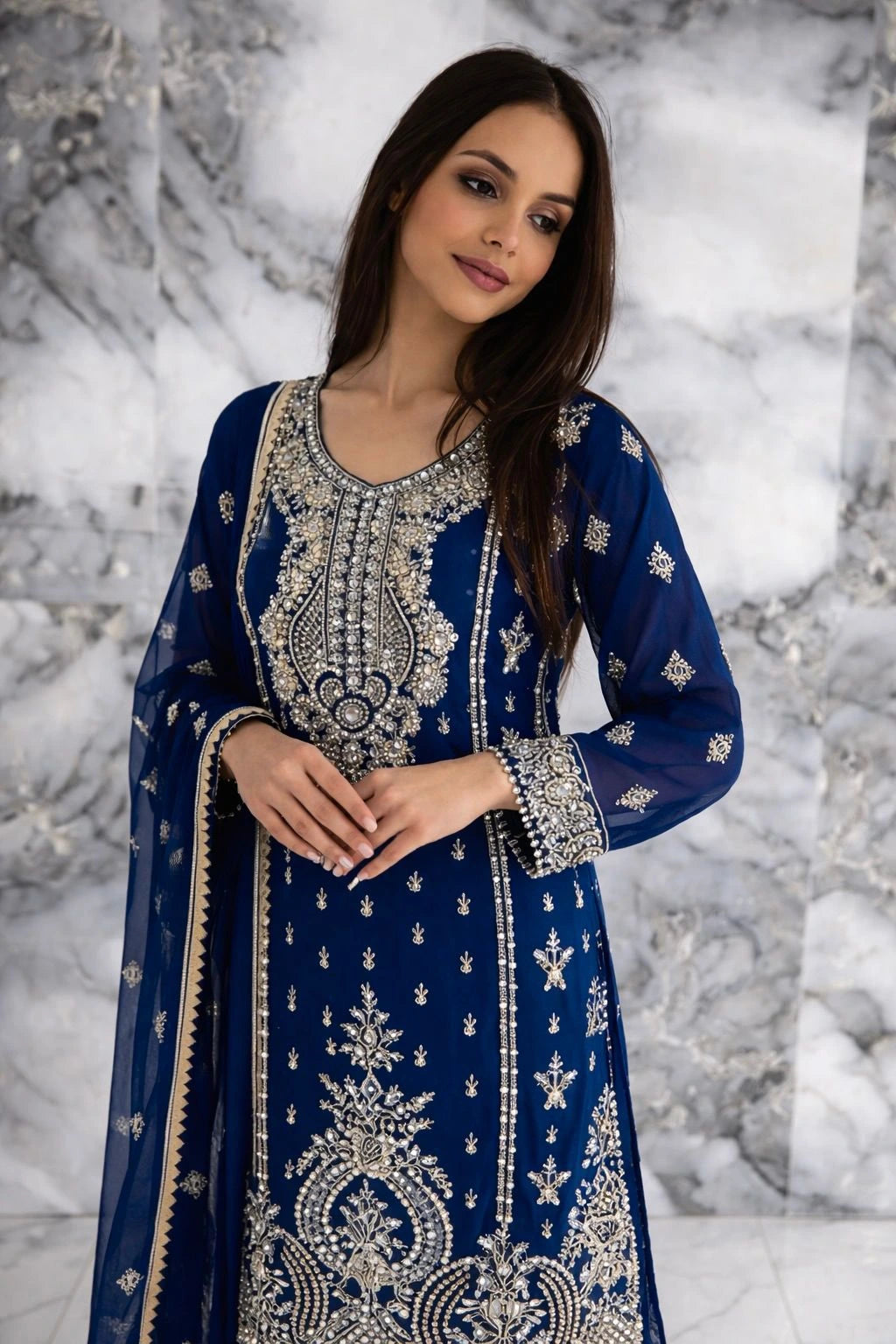 Woman wearing a blue embroidered traditional outfit against a marble background