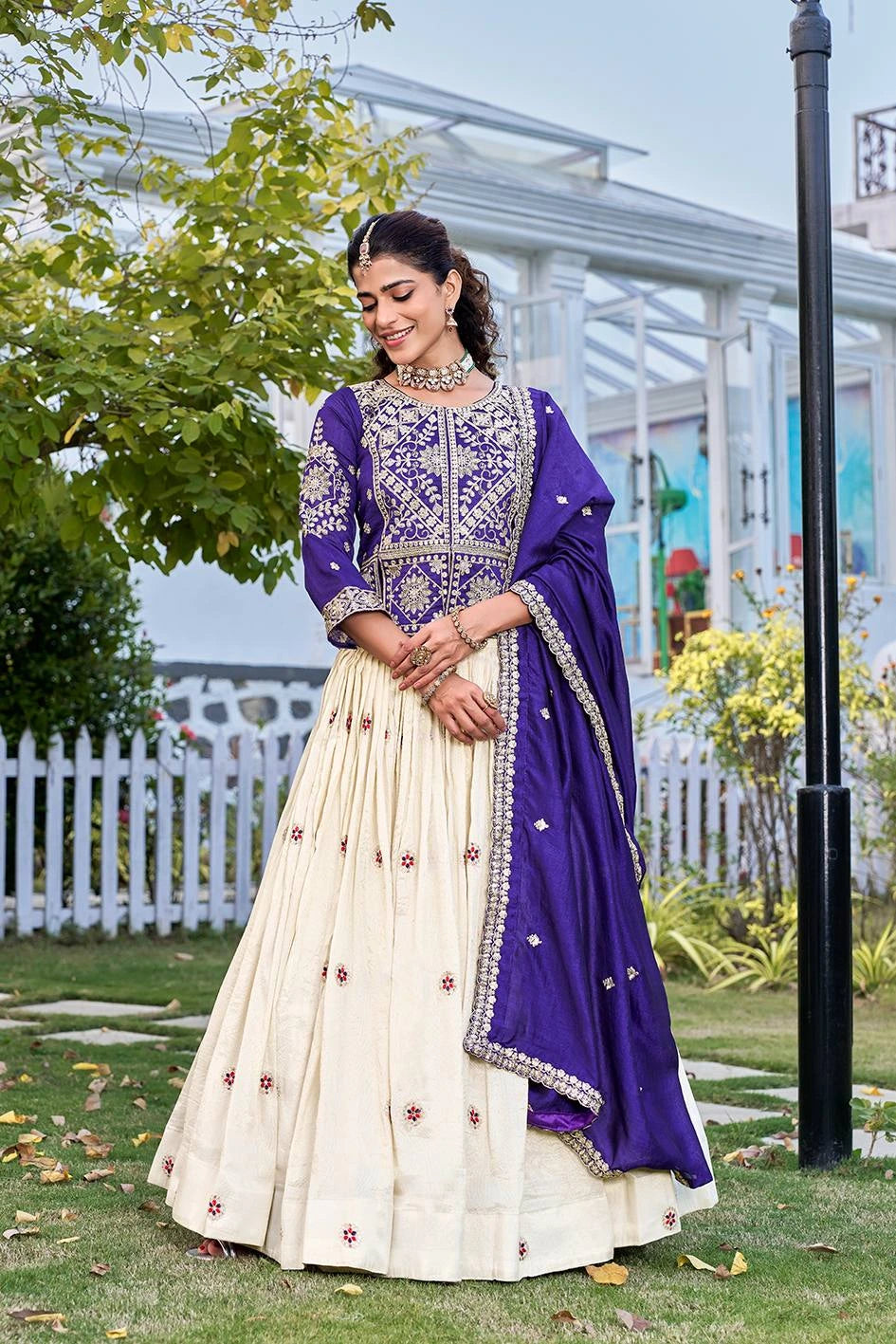 Woman wearing a purple tissue silk  Lehengas with heavy sequins and thread embroidery paired with a cream lehenga, styled for festive occasions.