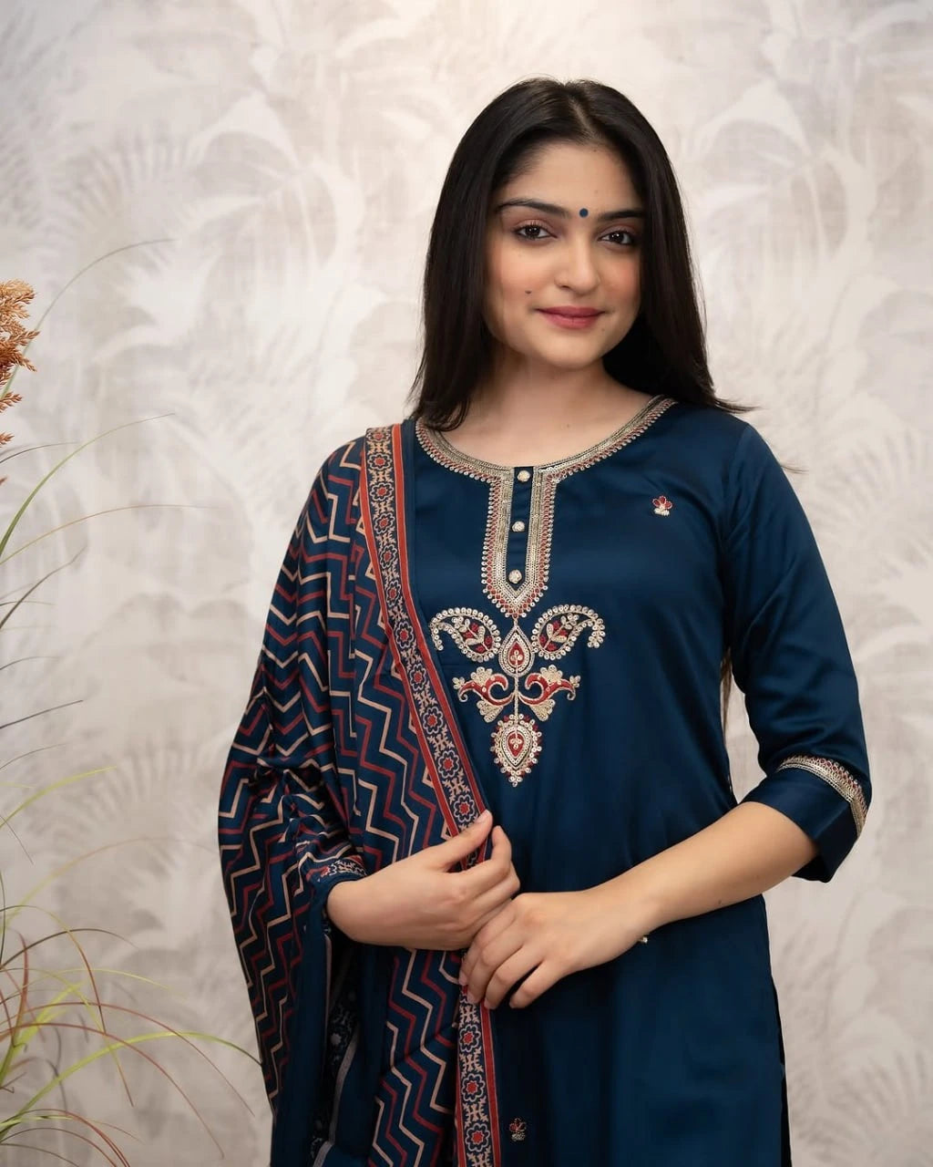 Woman wearing a blue embroidered kurta with a patterned dupatta against a white background