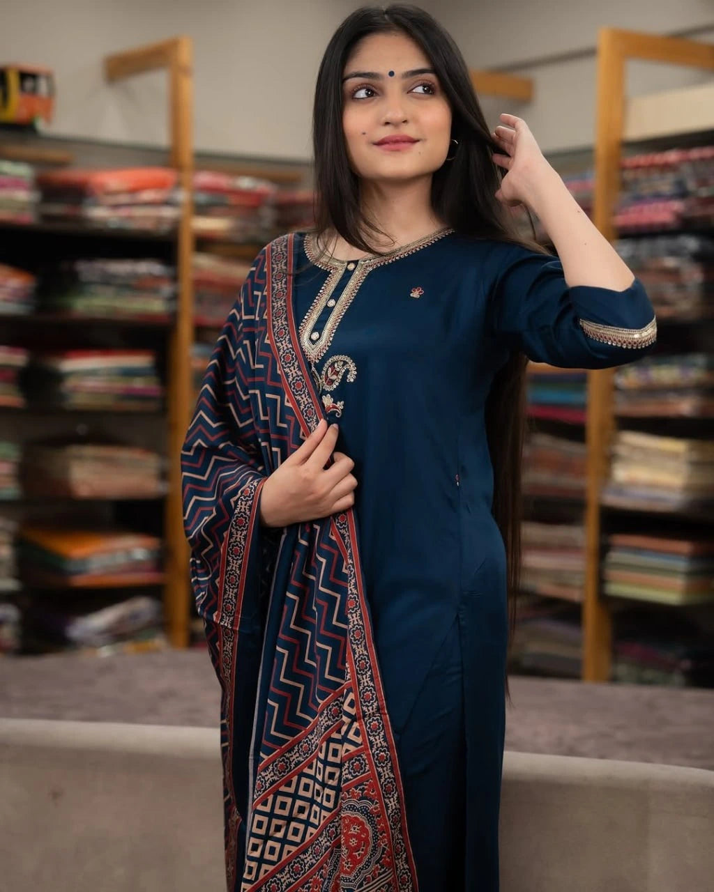 Woman in a blue traditional outfit with a patterned shawl in a library setting