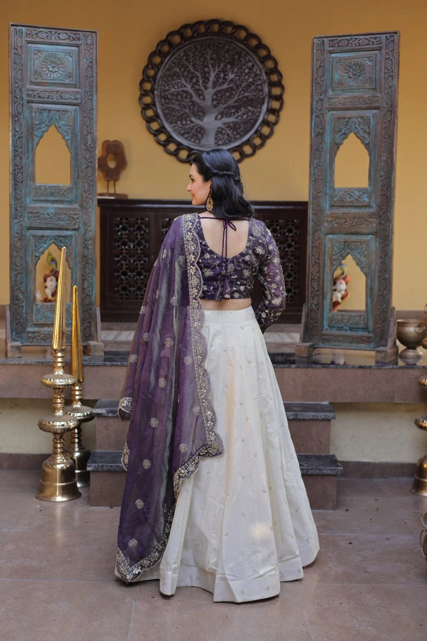 Woman in a traditional outfit with a purple dupatta in an indoor setting.