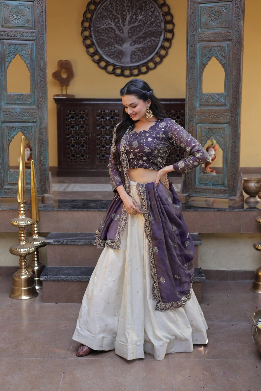 Woman in a traditional outfit with a purple top and white skirt in an ornate room.