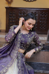Woman in a purple traditional outfit adjusting her earrings indoors.
