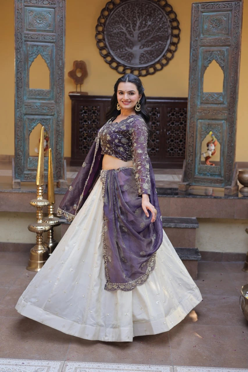 Woman in a traditional outfit with purple and white colors in an ornate room.