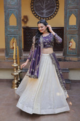 Woman in a traditional outfit with a purple top and white skirt in an ornate setting.