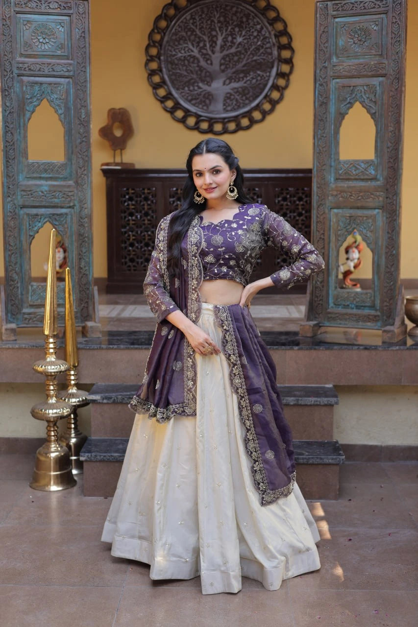 Woman in traditional outfit with purple and white design in a decorated room.