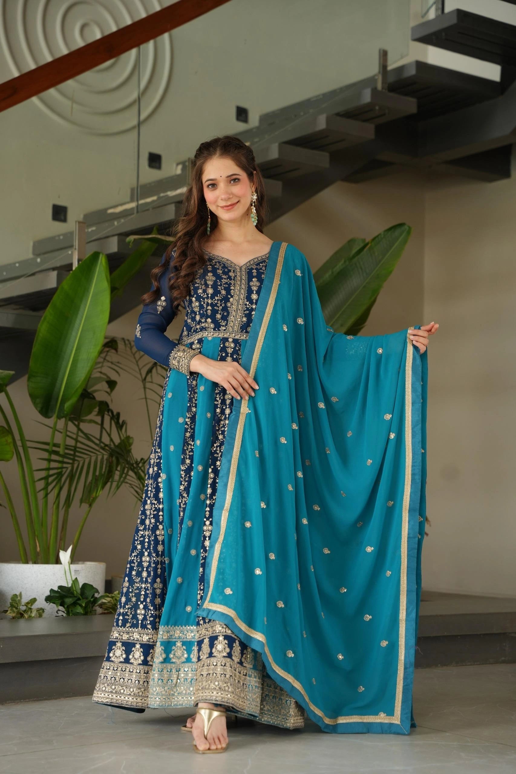 Woman in a blue traditional outfit with a matching dupatta in an indoor setting.