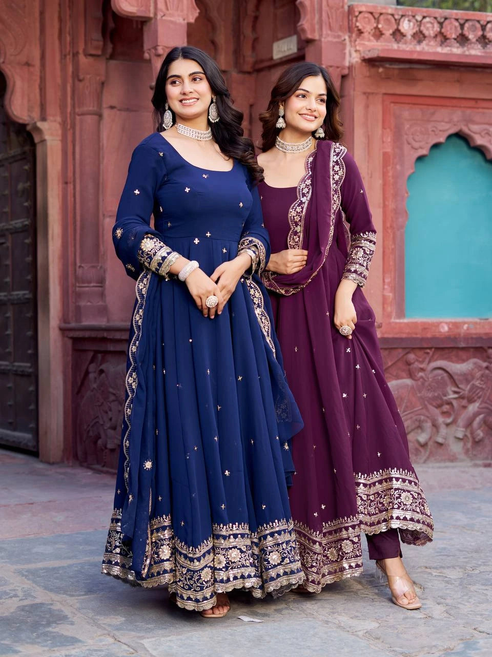A woman poses elegantly in a navy blue embroidered ethnic gown with a matching dupatta.
