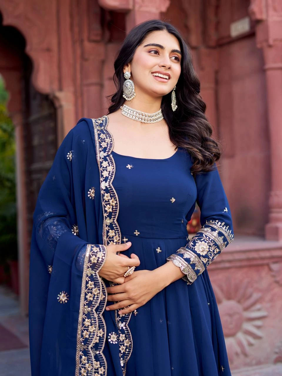 She accessorizes with statement earrings, a choker necklace, and rings for a festive look.
