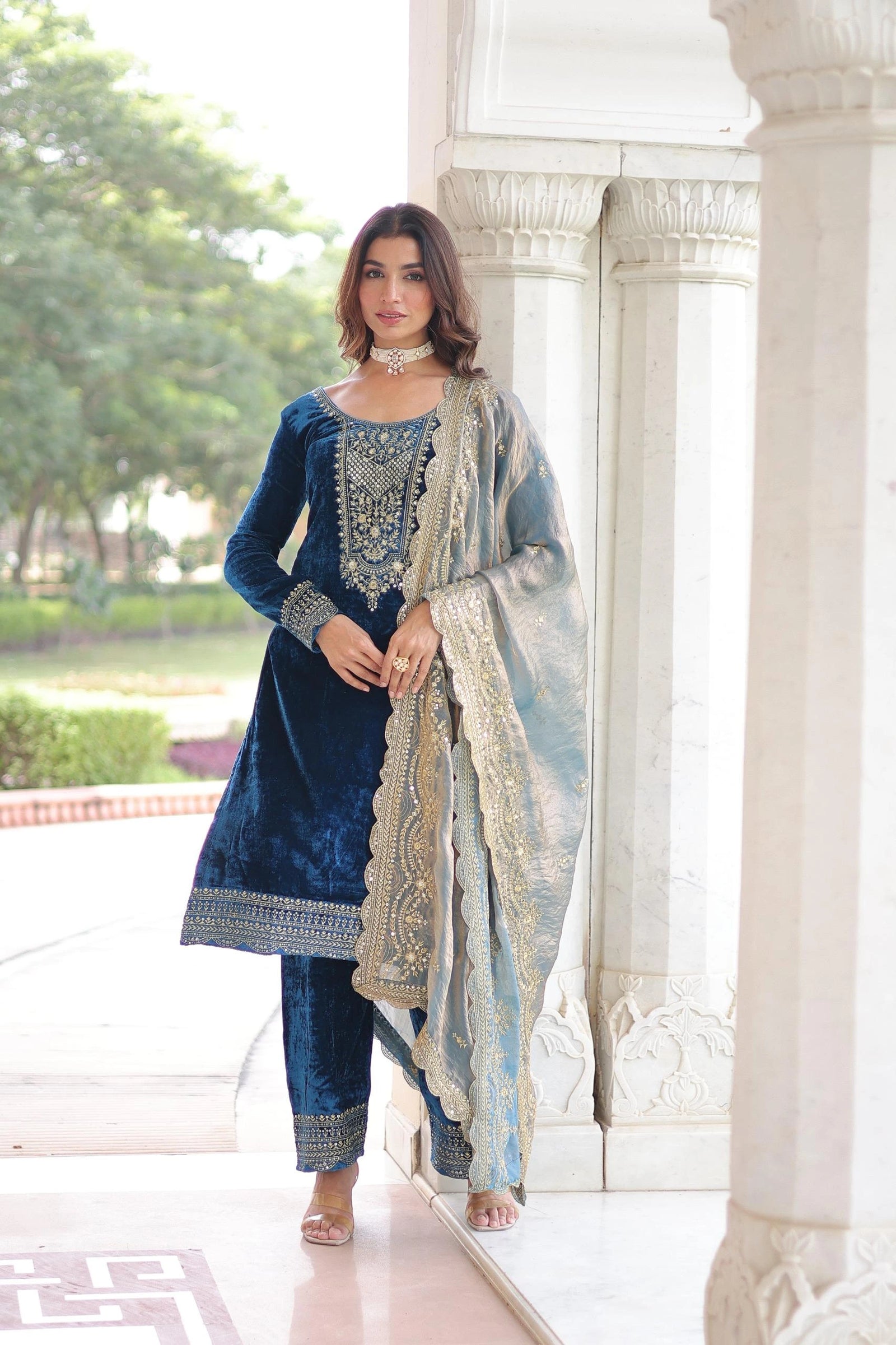 Woman in traditional blue embroidered outfit with a white background