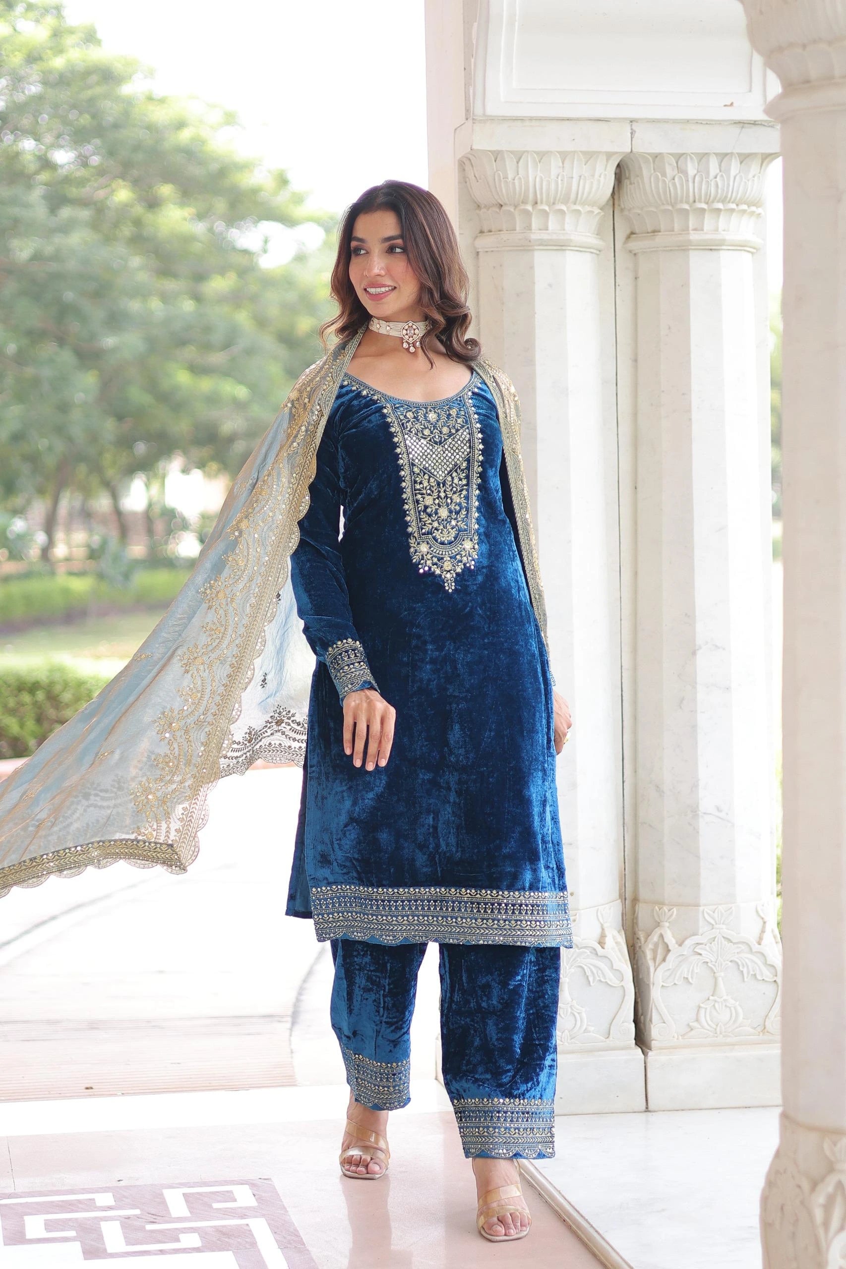 Woman wearing a blue embroidered outfit with a white background