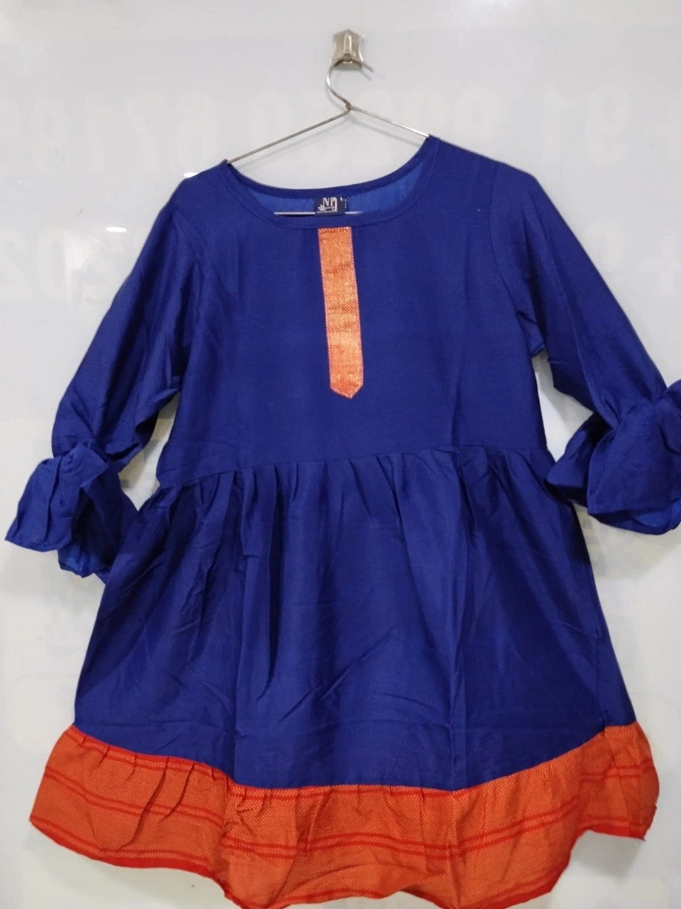 Blue dress with orange bottom section on a hanger against a white background