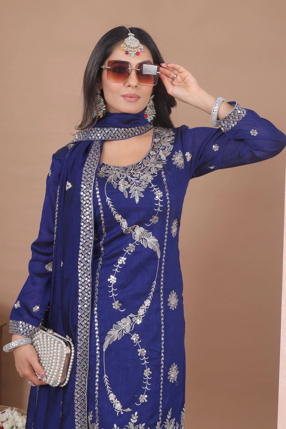 Woman wearing a blue embroidered traditional outfit with silver details on a brown background