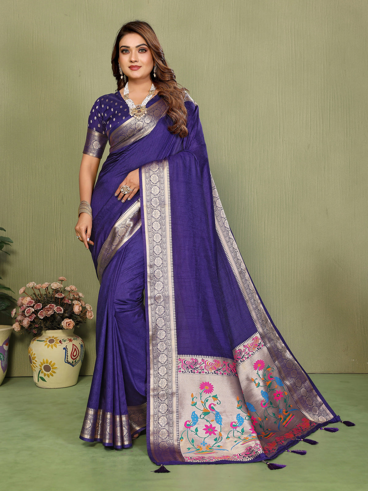 Woman wearing a purple saree with floral patterns on a green background