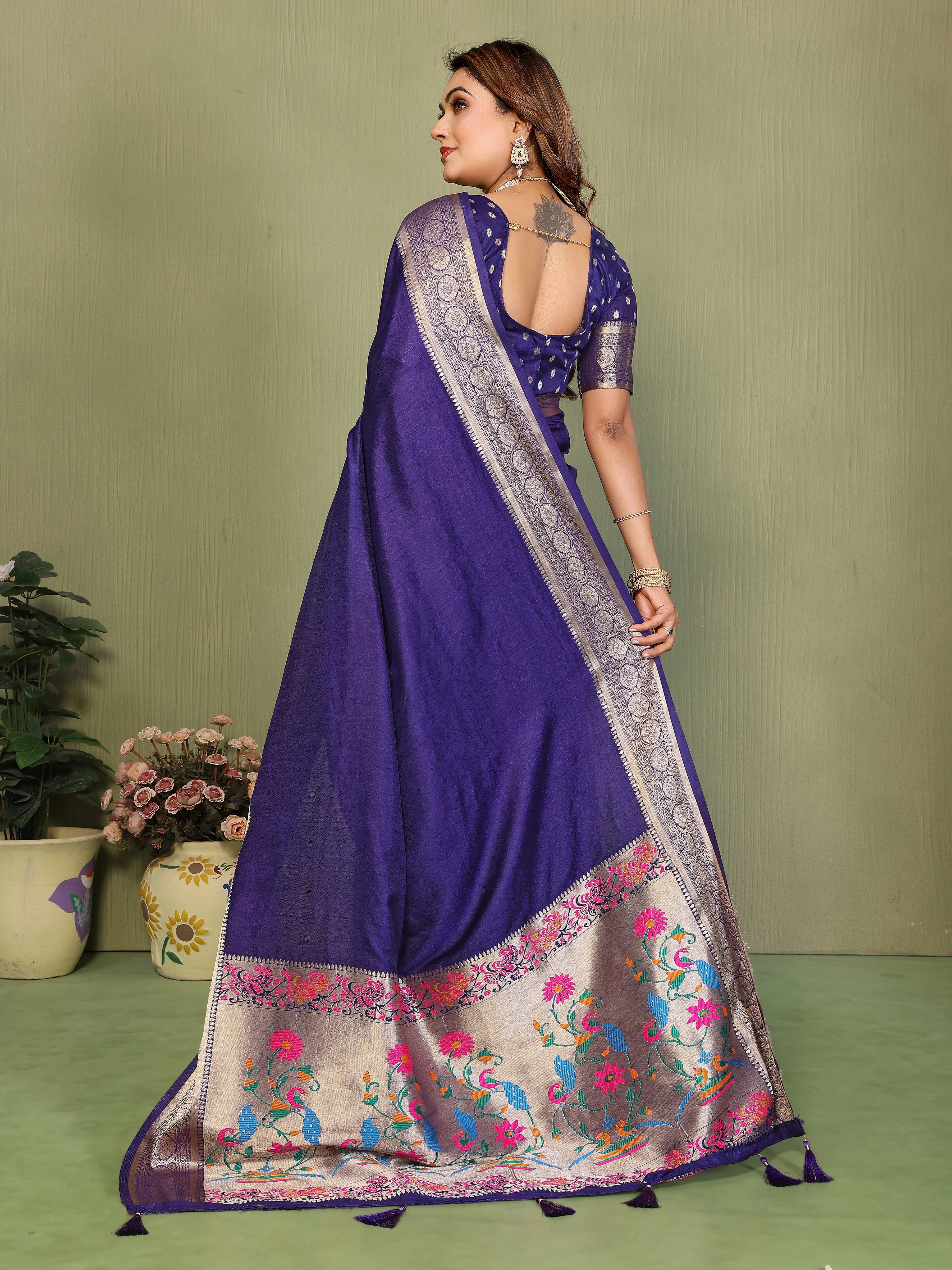 Woman wearing a purple saree with floral patterns on a green background