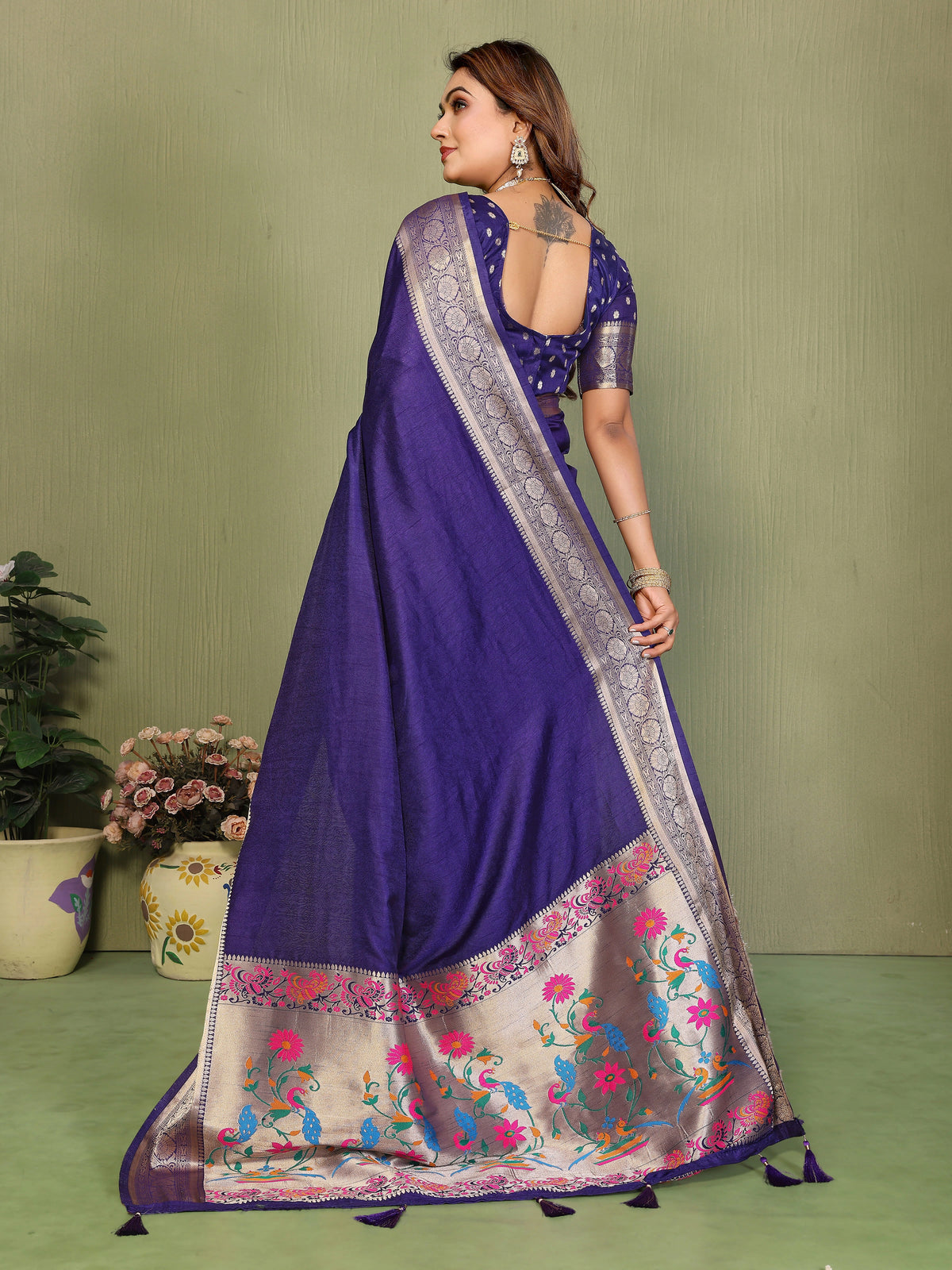 Woman wearing a purple saree with floral patterns on a green background