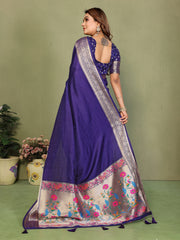 Woman wearing a purple saree with floral patterns on a green background
