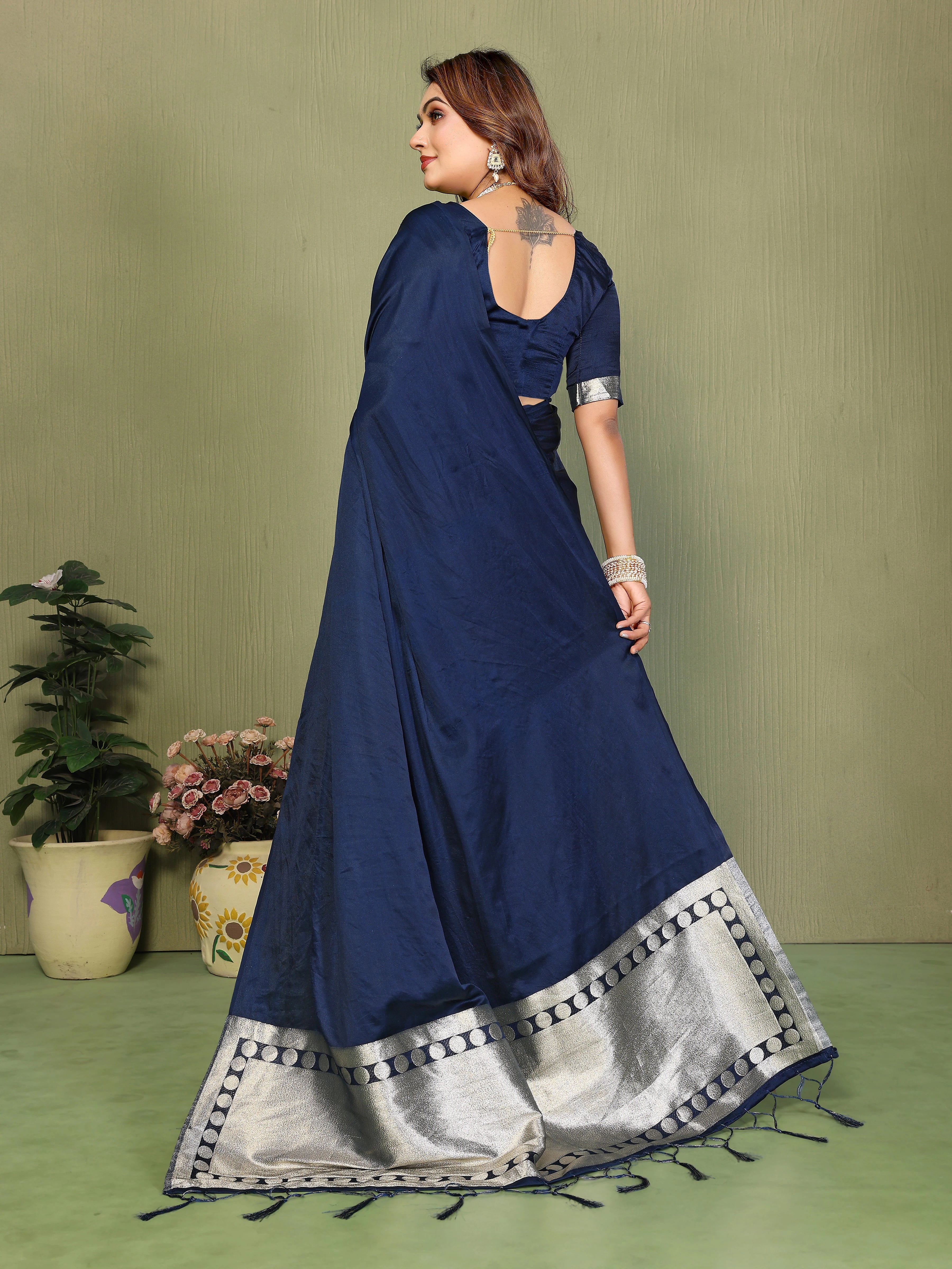 Woman wearing a blue saree with silver border against a green background