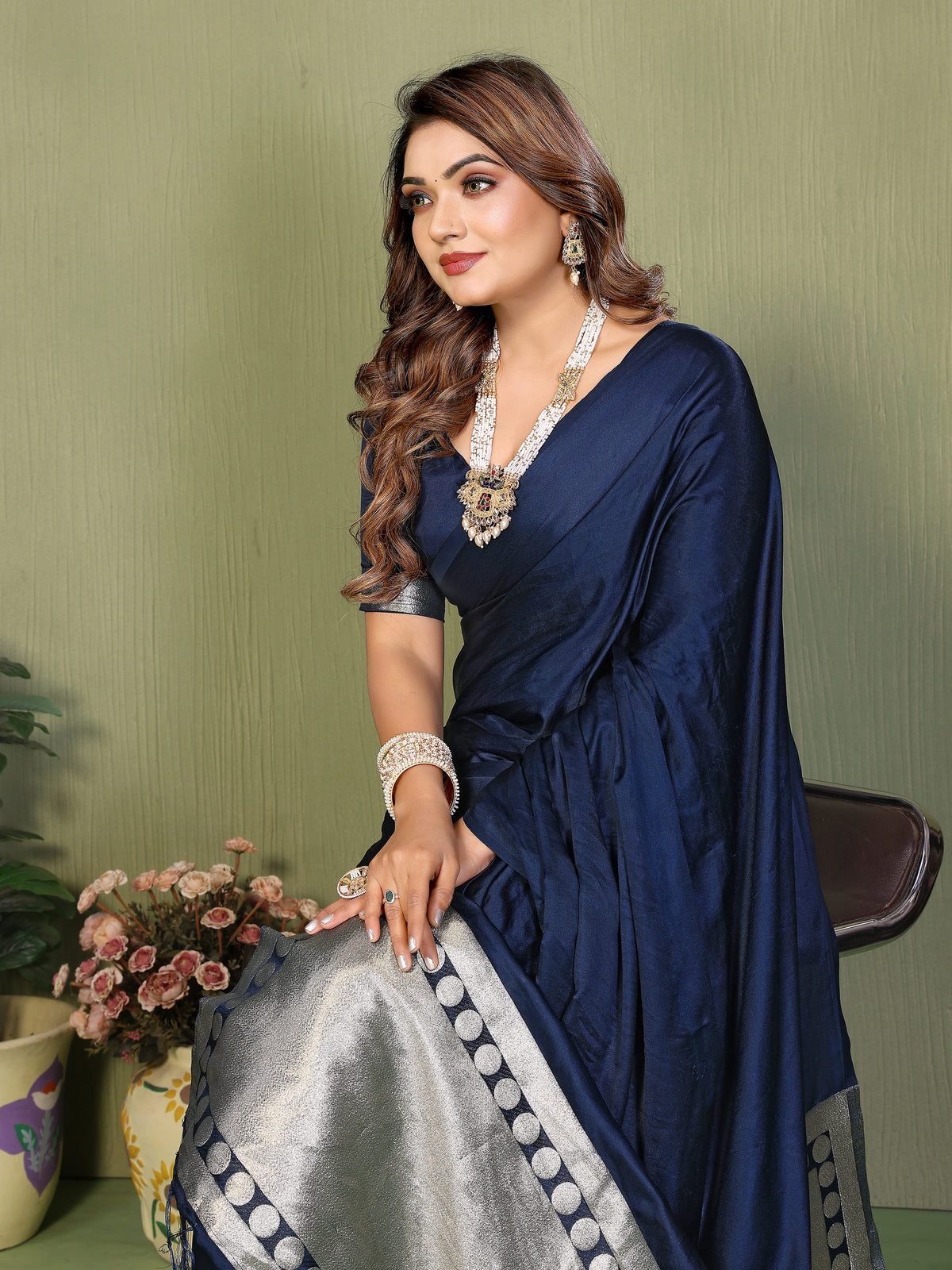 Woman wearing a navy blue saree with a green background