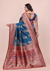 Woman wearing a blue and red saree with intricate patterns on a beige background