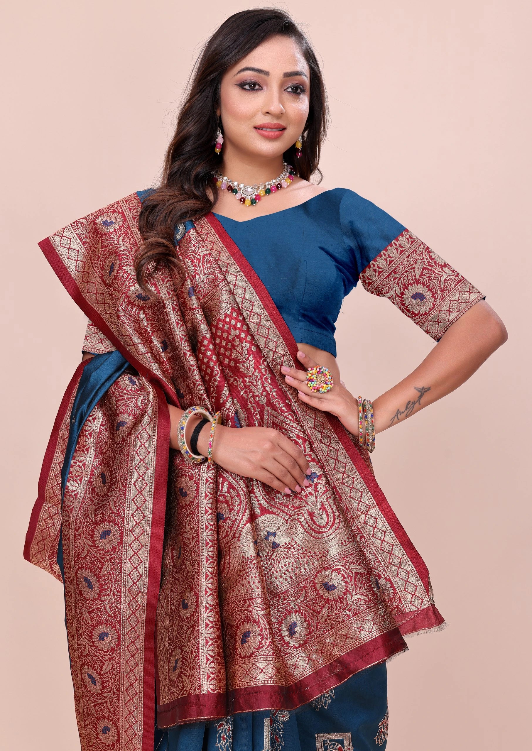 Woman wearing a blue blouse with a red and gold saree on a beige background