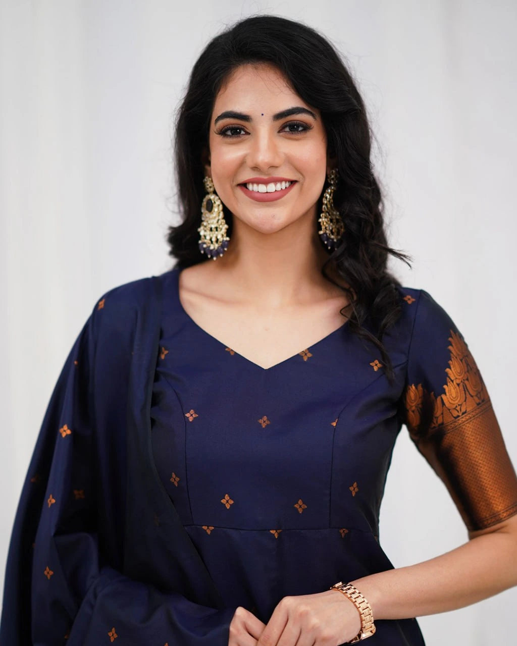 Woman wearing a navy blue traditional outfit with gold patterns on a white background