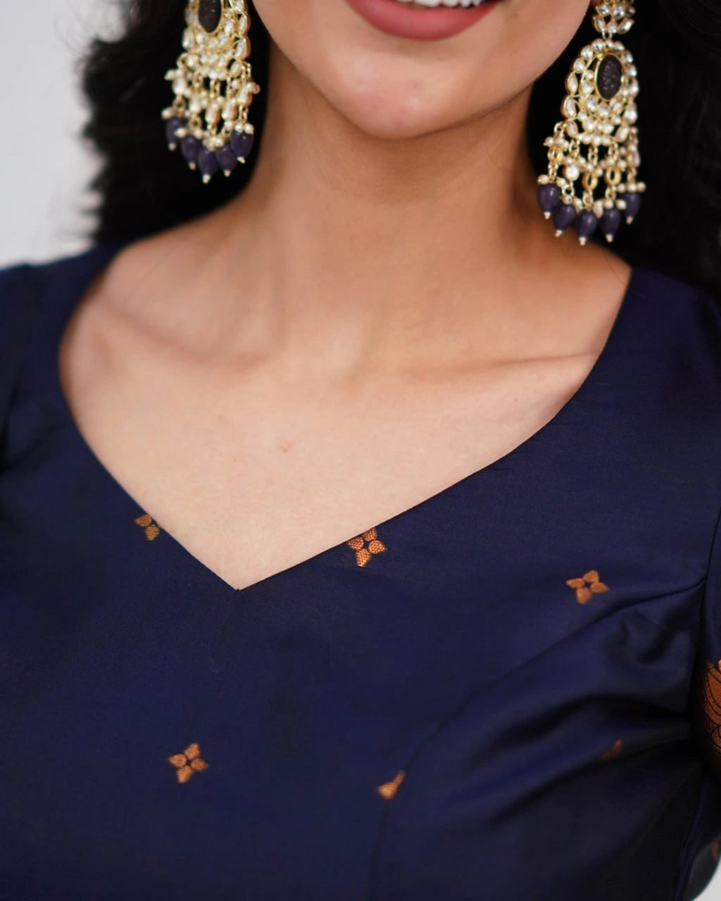 Navy blue saree with gold embroidery and matching earrings.