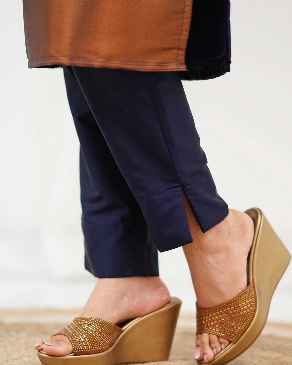 Person wearing brown wedge sandals with a neutral background