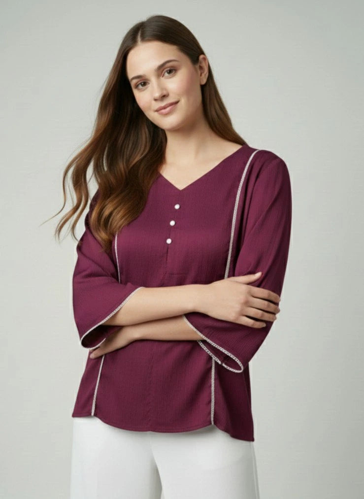 Woman wearing a purple blouse with white trim on a plain background