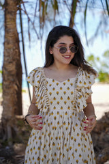 Woman wearing a white dress with yellow patterns outdoors