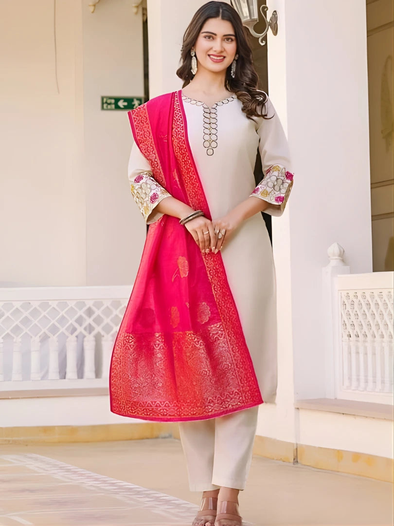 Woman wearing a white outfit with a pink dupatta in an indoor setting