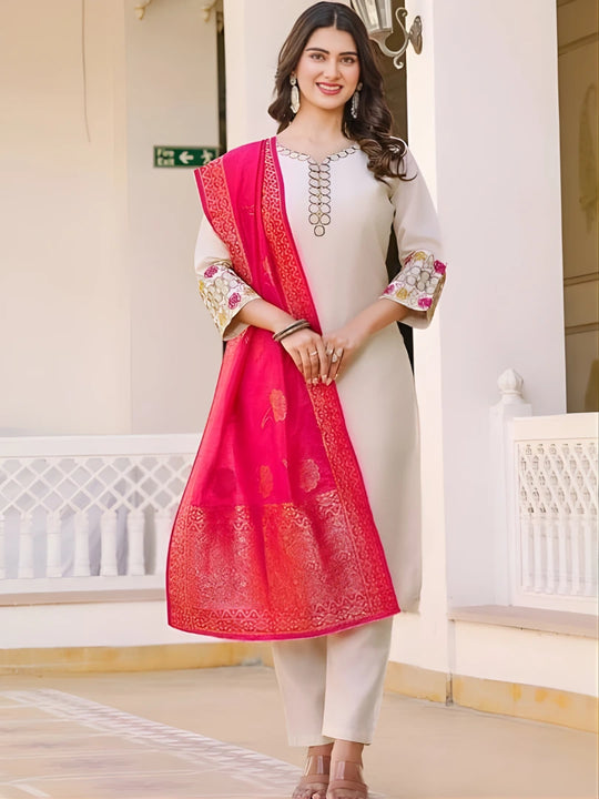 Woman wearing a white outfit with a pink dupatta in an indoor setting