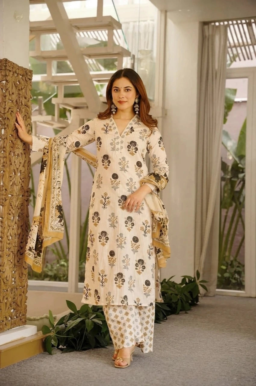 Woman in a floral dress standing indoors with plants and a window in the background