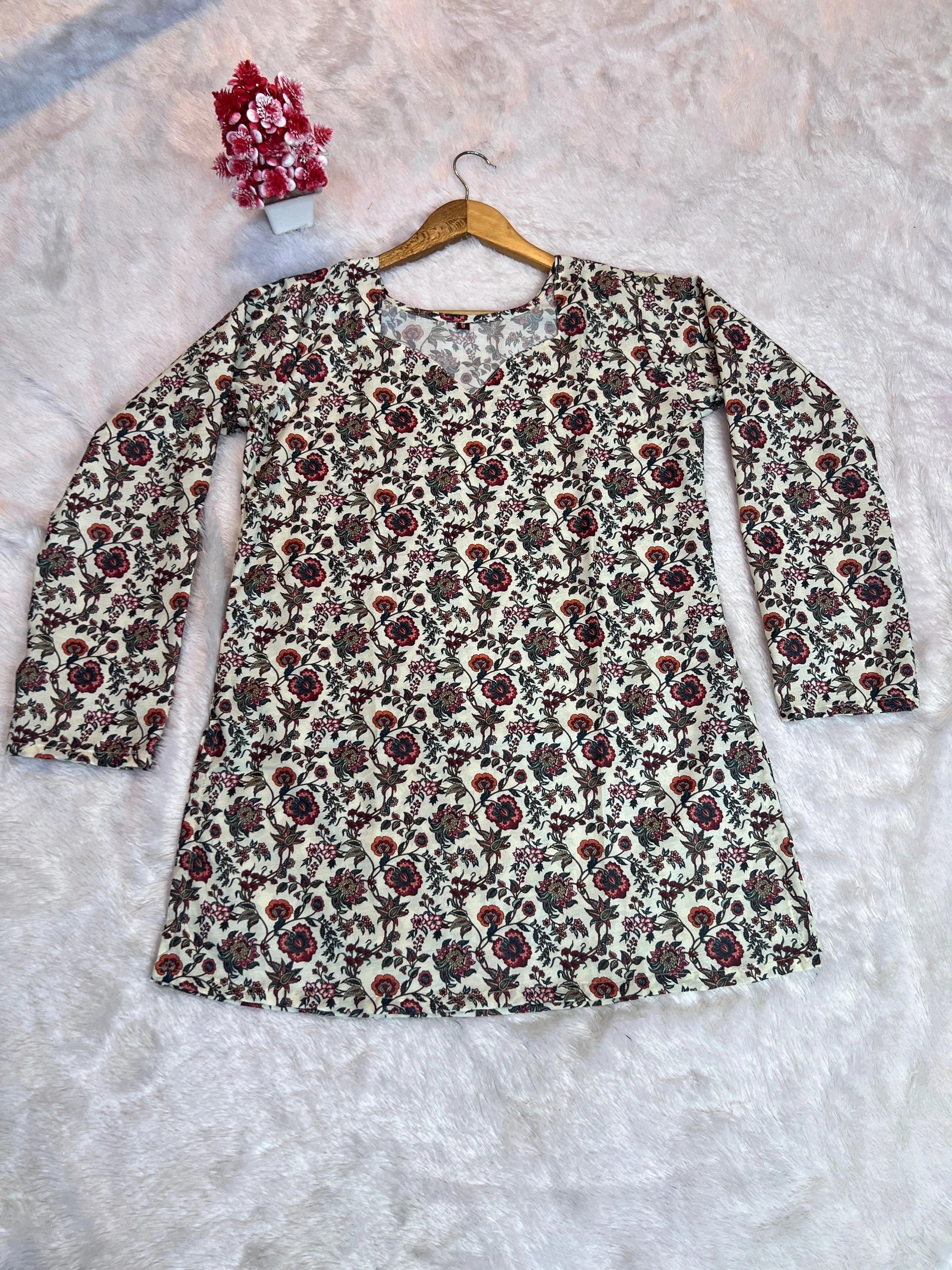 Floral patterned dress on a hanger against a textured white background