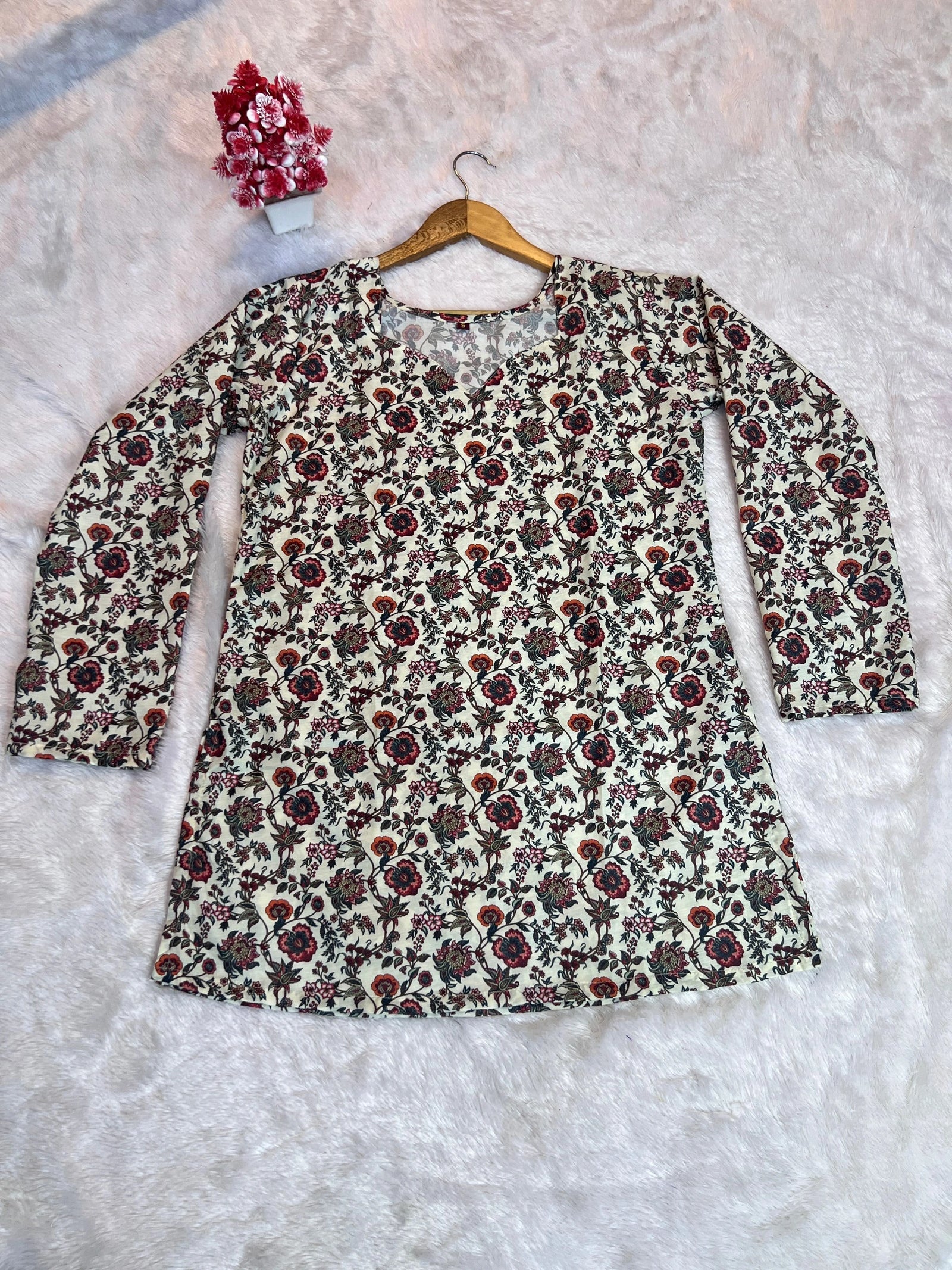 Floral patterned dress on a hanger against a textured white background