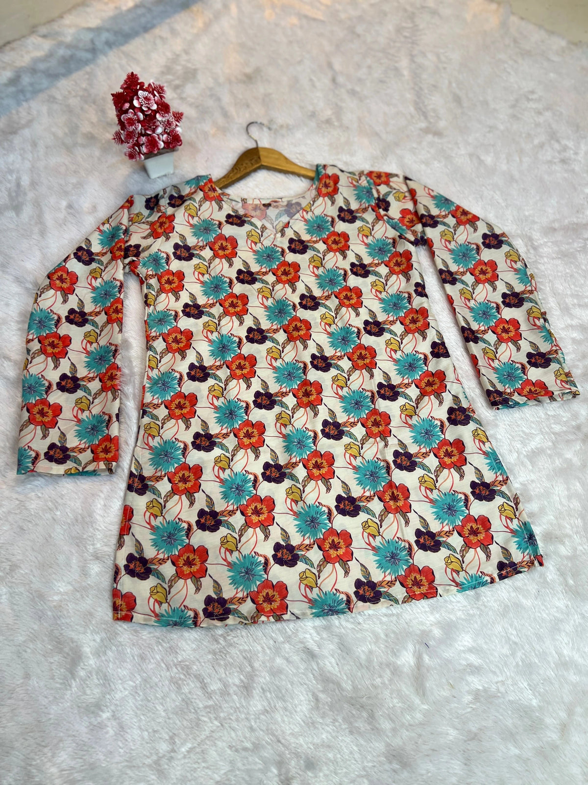 Floral dress with long sleeves on a hanger against a textured white background