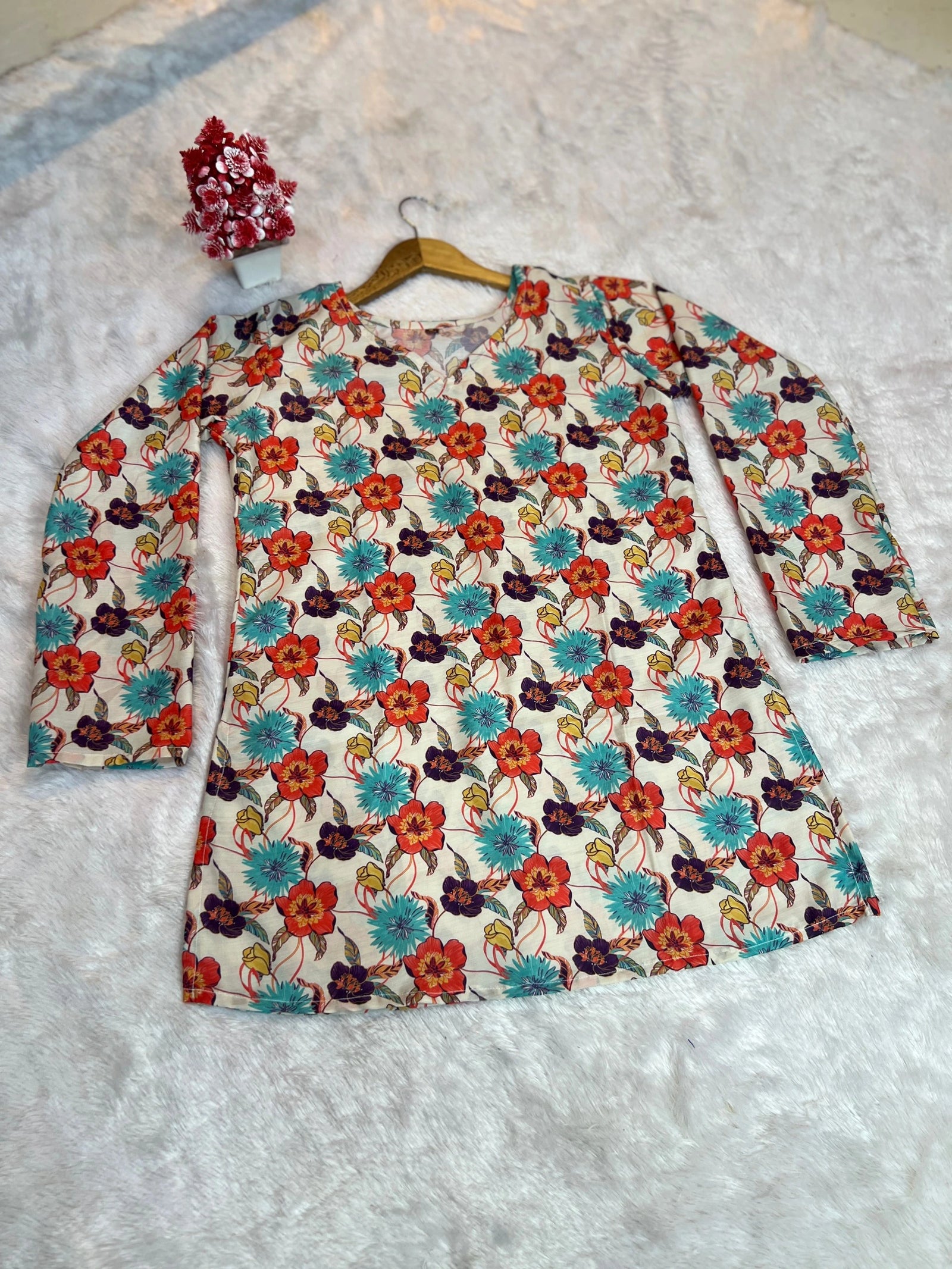 Floral dress with long sleeves on a hanger against a textured white background
