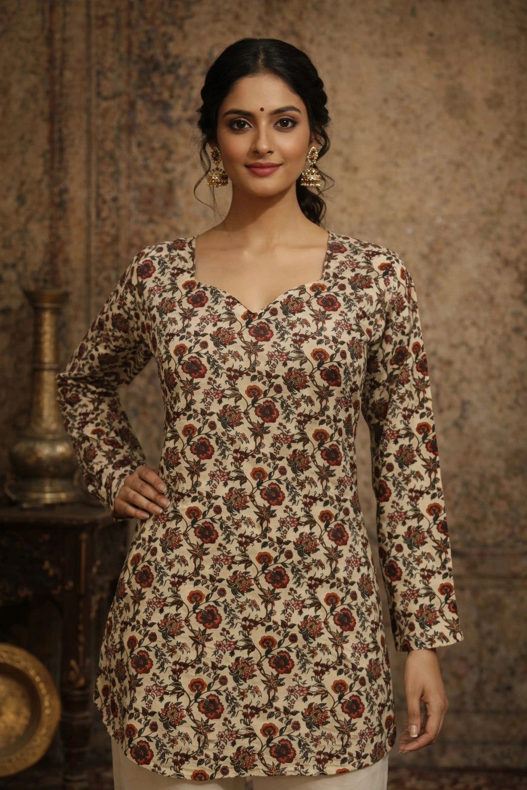 Woman wearing a floral patterned kurta against a textured wall.