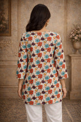 Woman wearing a floral patterned top in a room with wooden walls and a vase.