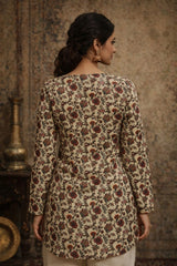 Woman wearing a floral patterned top in a warm-toned setting