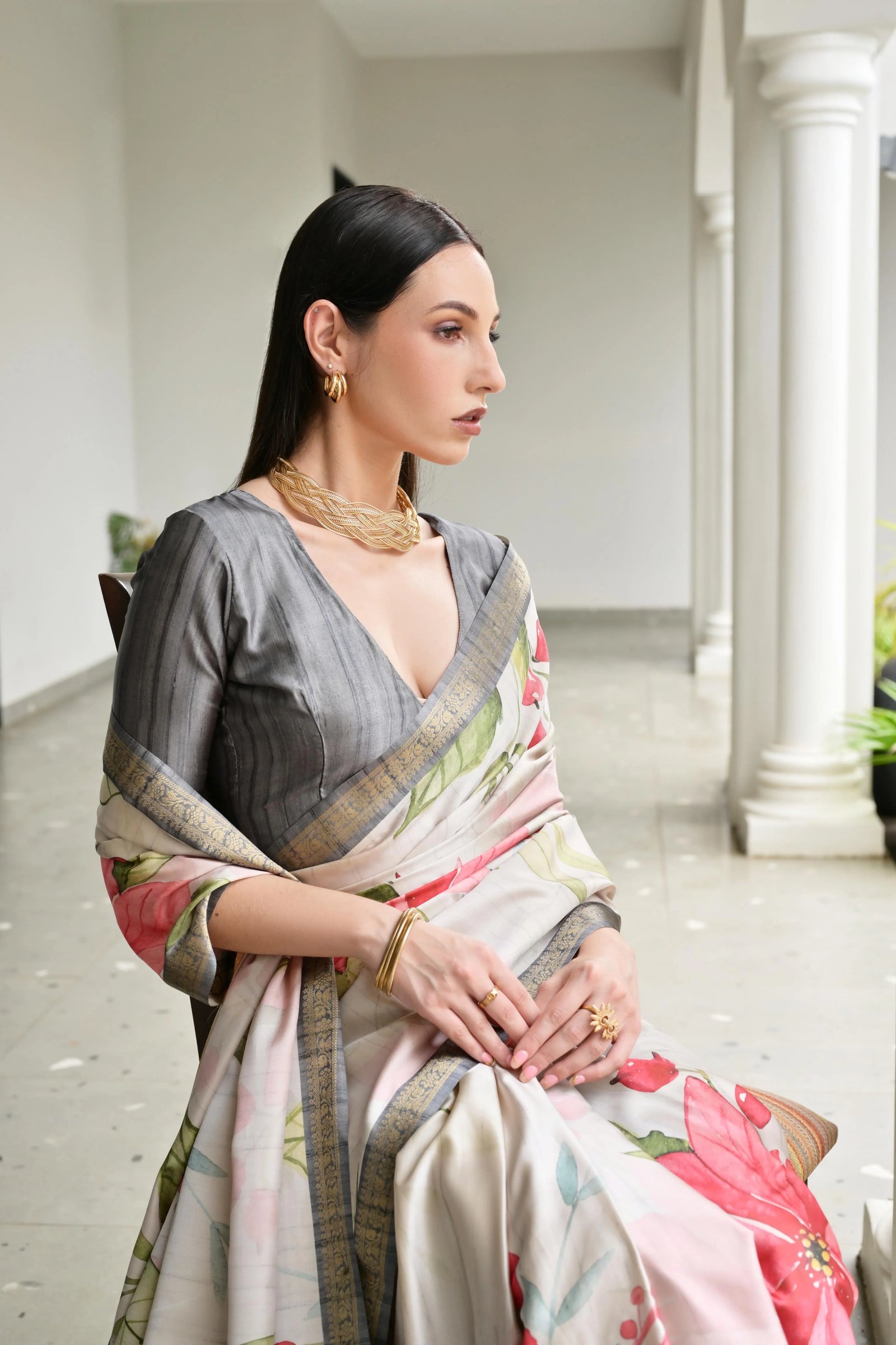 Woman in a floral saree sitting in an elegant indoor setting
