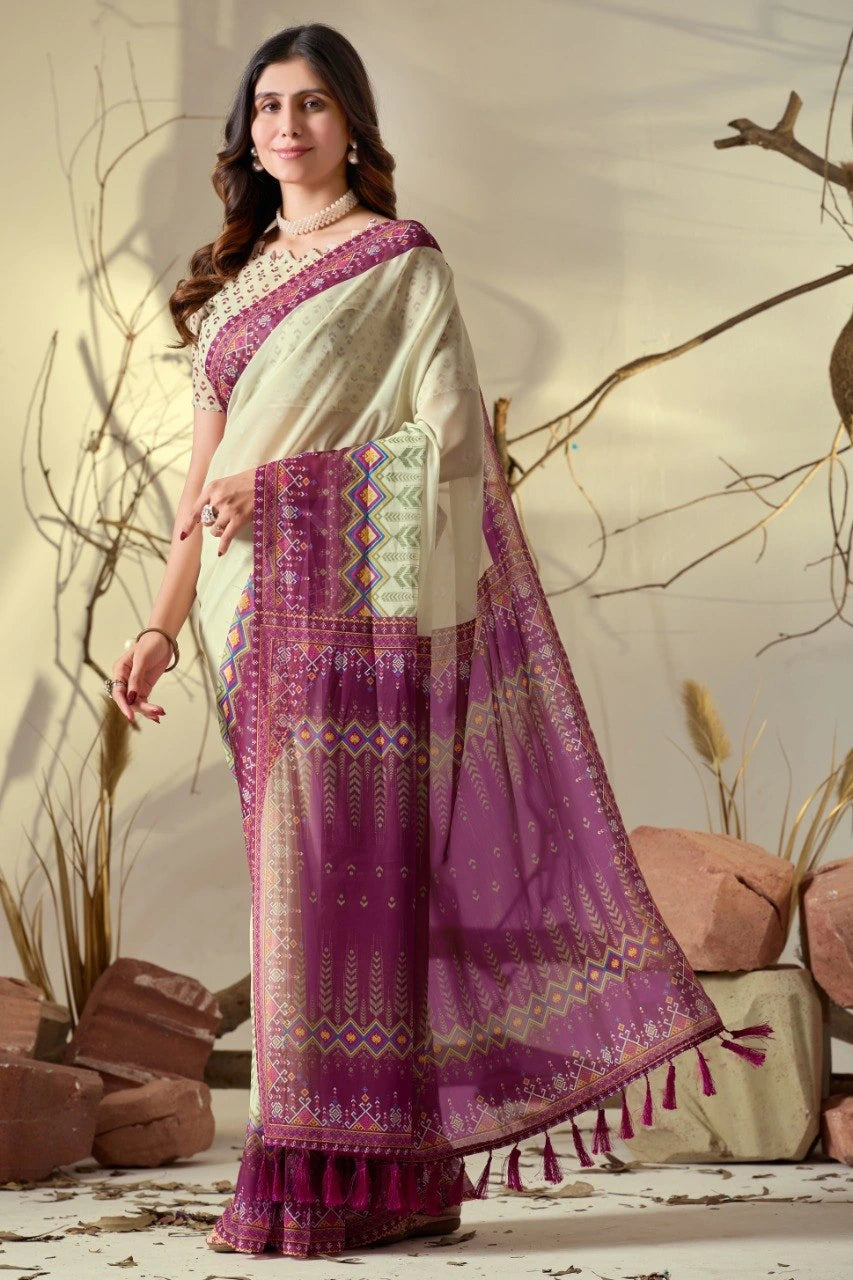 Woman wearing a traditional saree with a purple and white design, standing against a natural background.