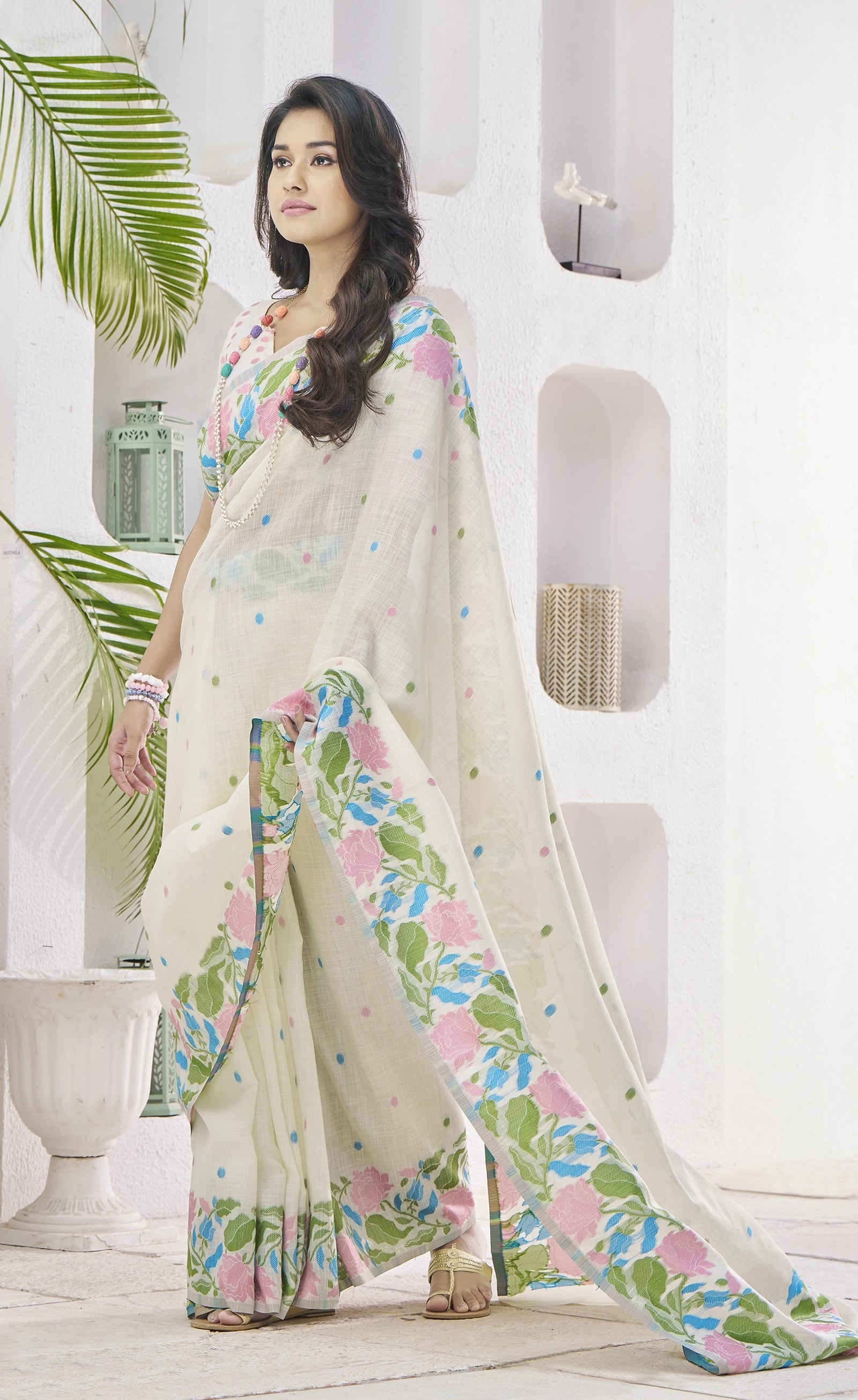 Woman wearing a floral saree in a white room with plants