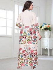 Woman wearing a floral dress in a bright room with white walls and a vase of flowers on a table.
