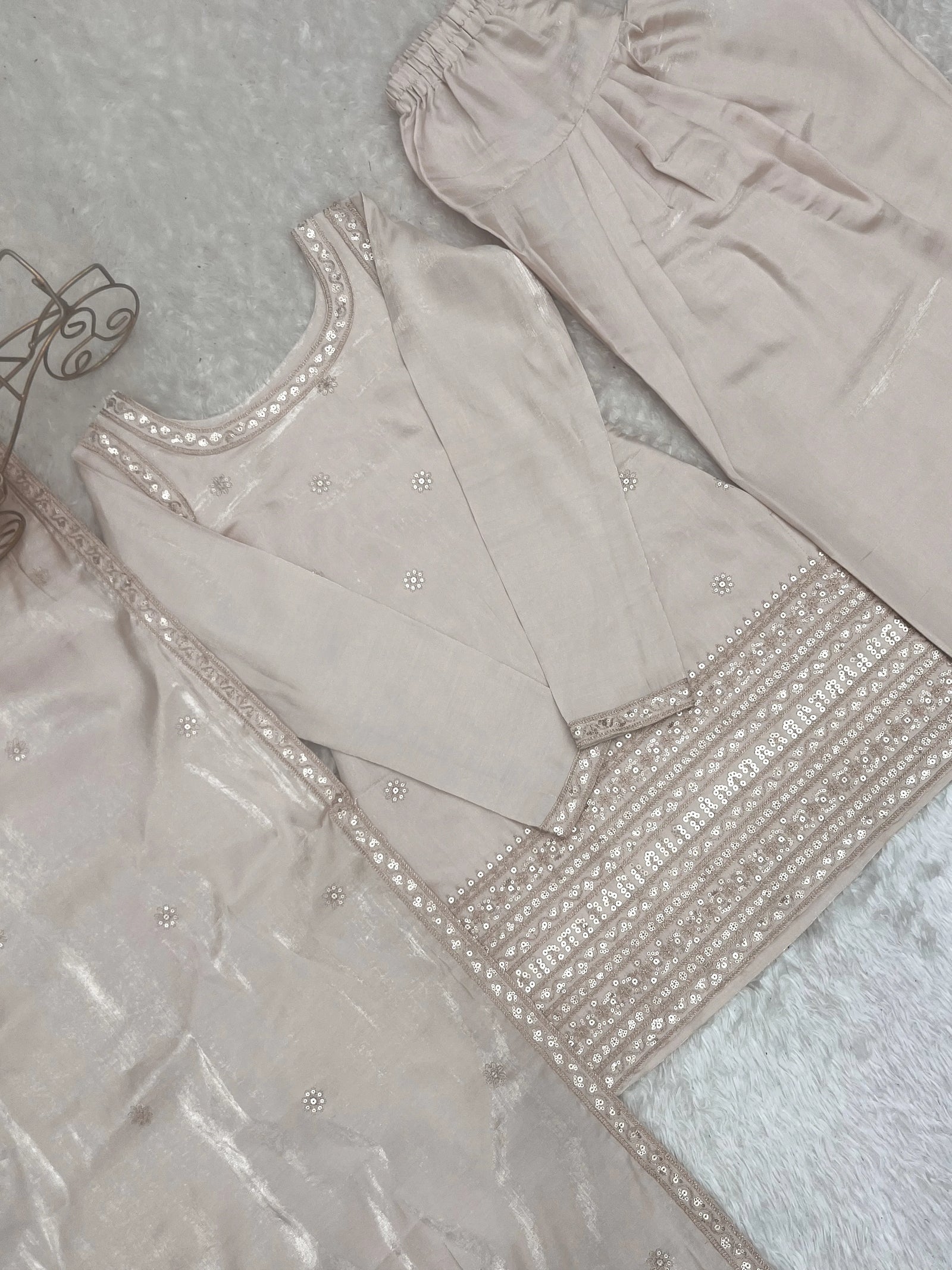 Light pink traditional outfit with intricate embroidery on a textured surface