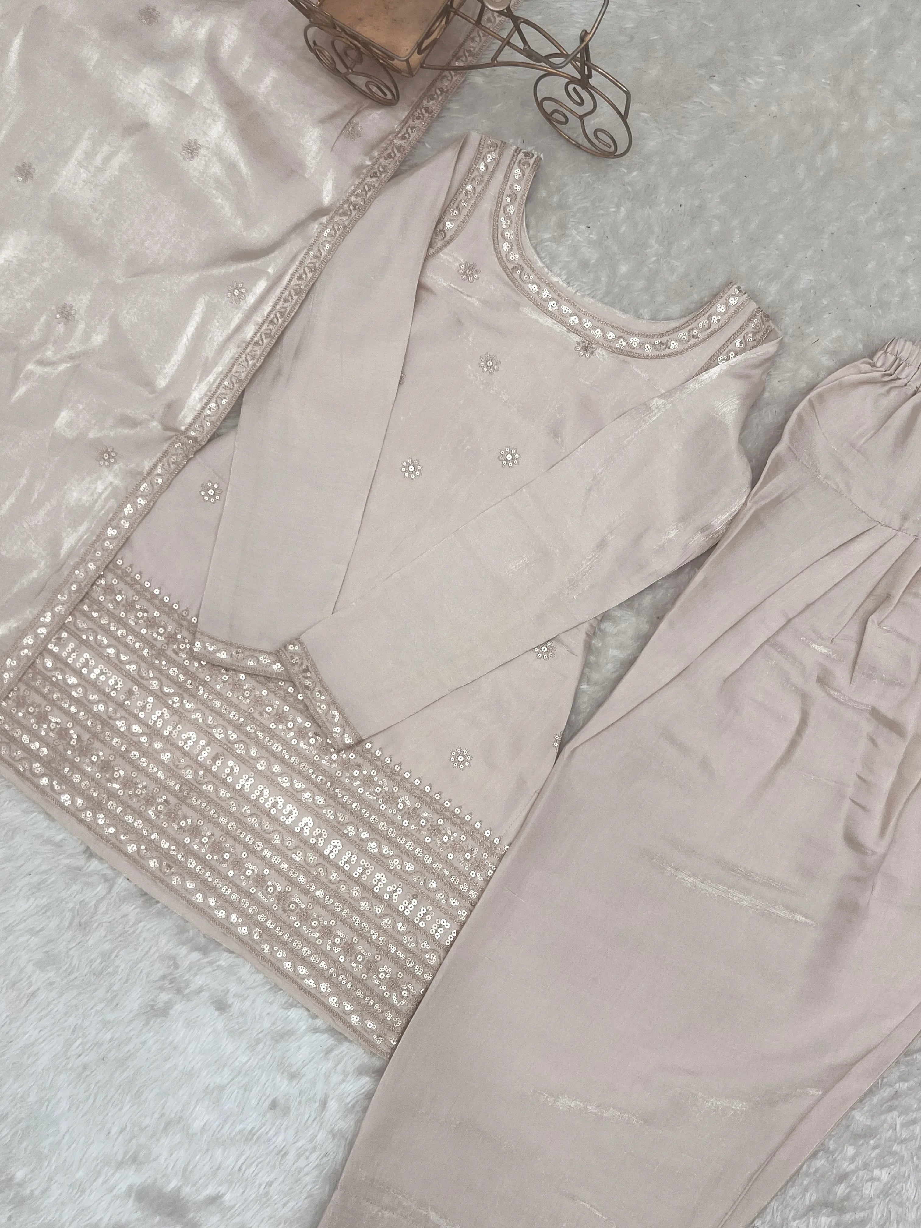 Light gray traditional outfit with intricate embroidery on a textured surface