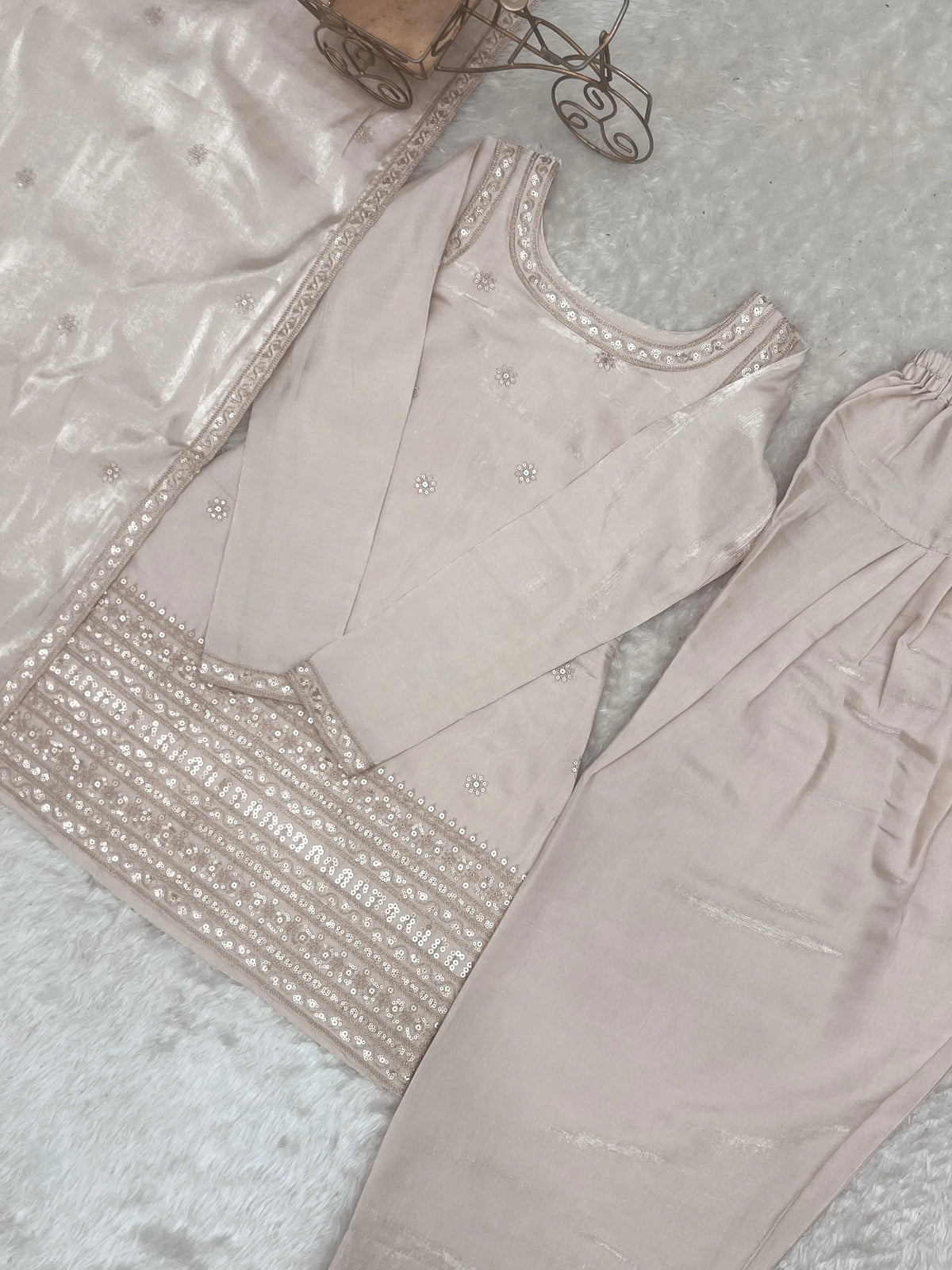 Light gray traditional outfit with intricate embroidery on a textured surface