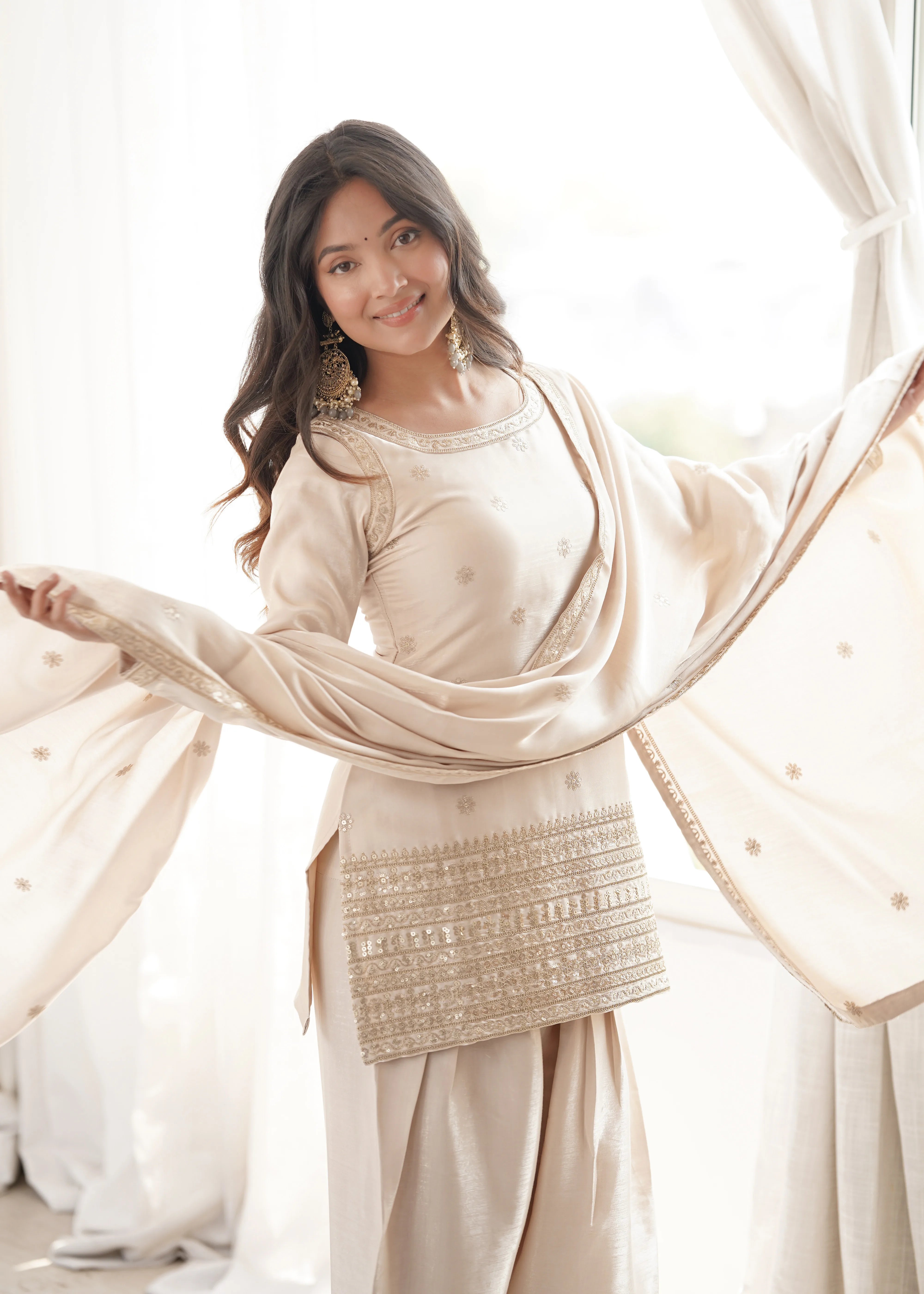 Woman in a traditional outfit with a beige dupatta in a bright setting